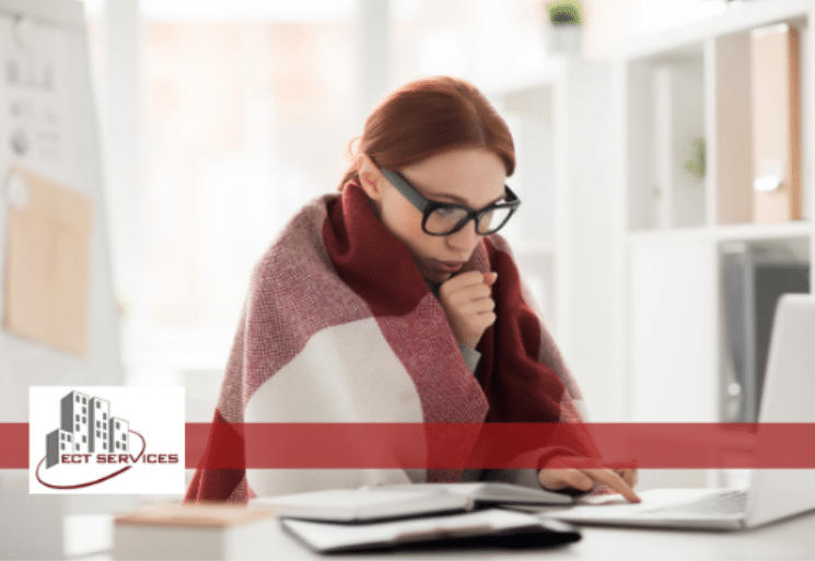 Woman cold in front of her laptop with a blanket on